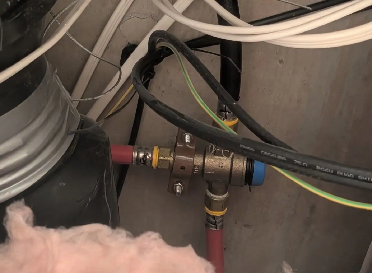Plumbing valve repair involving pipes and fittings in a residential kitchen.