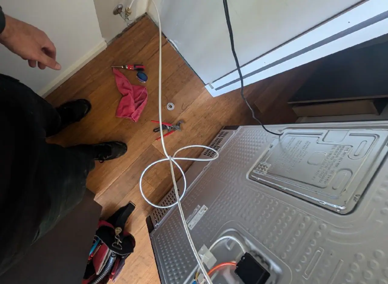 Blocked drain repair in a laundry room with plumbing tools and equipment.