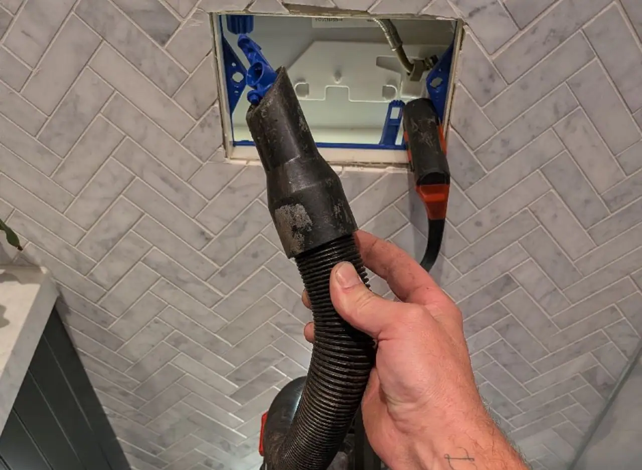 Drain cleaning in wall cavity with professional plumbing tools.