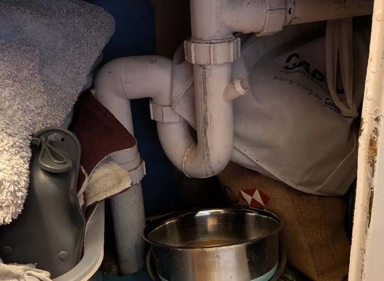 Under-sink plumbing with PVC pipes and fittings.