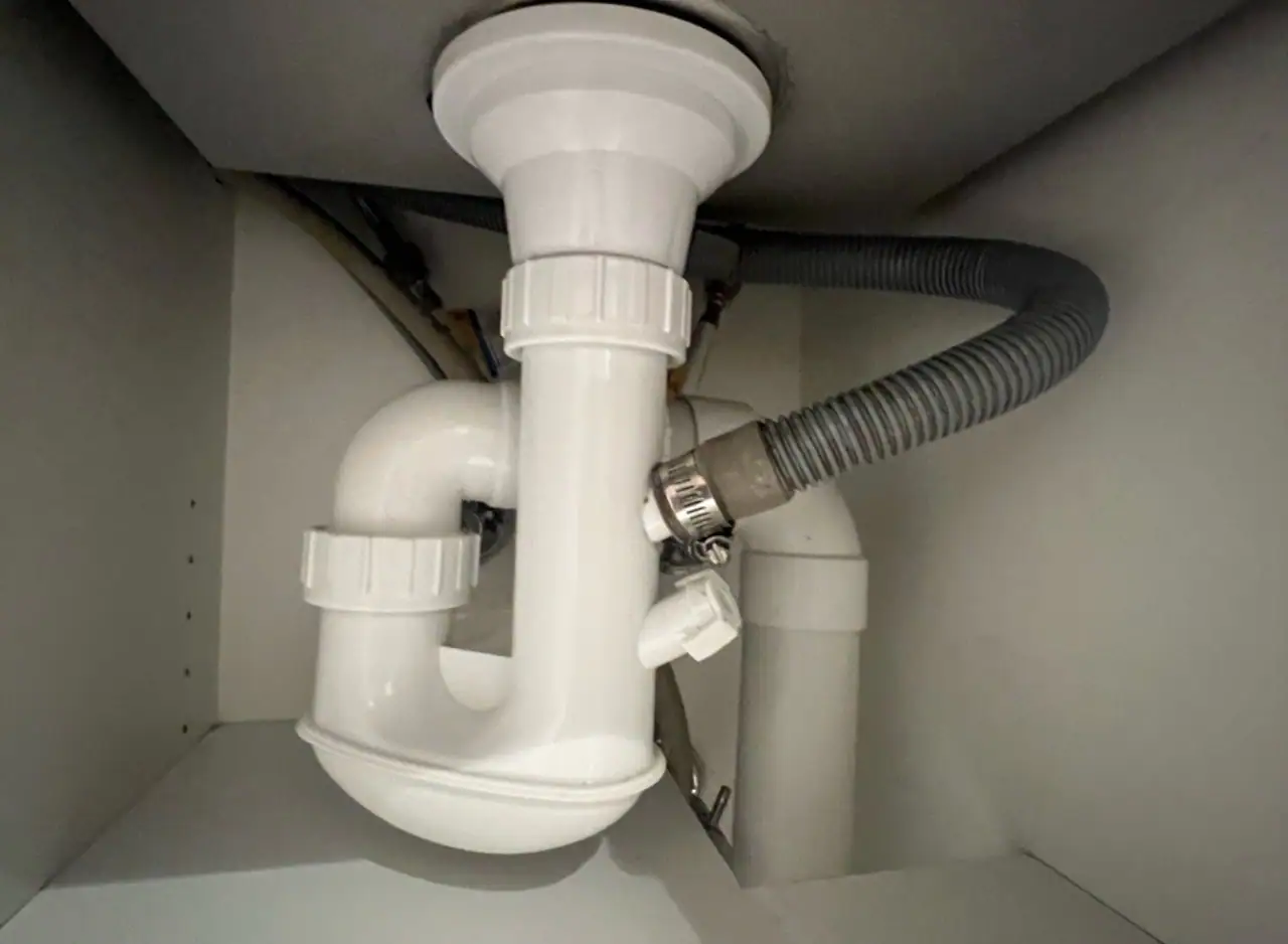 Kitchen sink drain pipe with plumbing repair and flexible hose connection.
