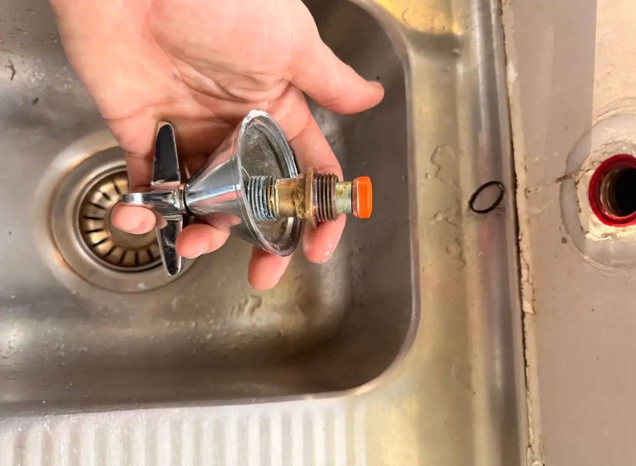 Plumber repairing water hammer issue with new valve in kitchen sink.