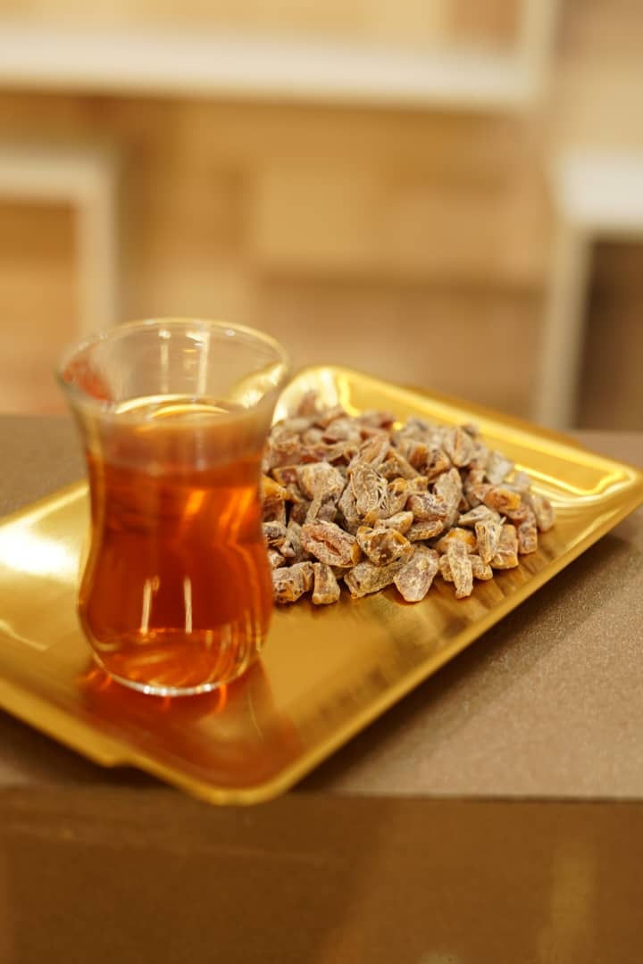 Flavored chopped dates on a gold tray with a glass of tea