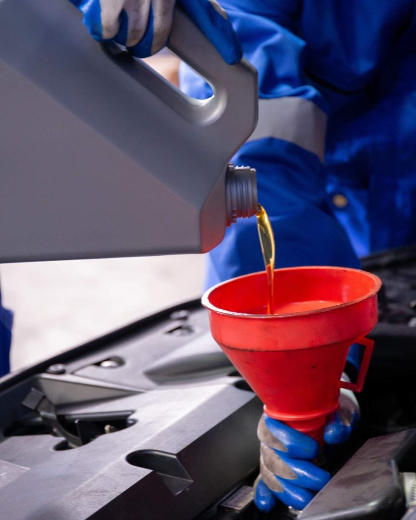 Pouring engine oil into car with funnel during maintenance.