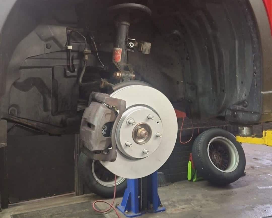 Close-up of a car's brake rotor and caliper during repair at Allen's QAC.