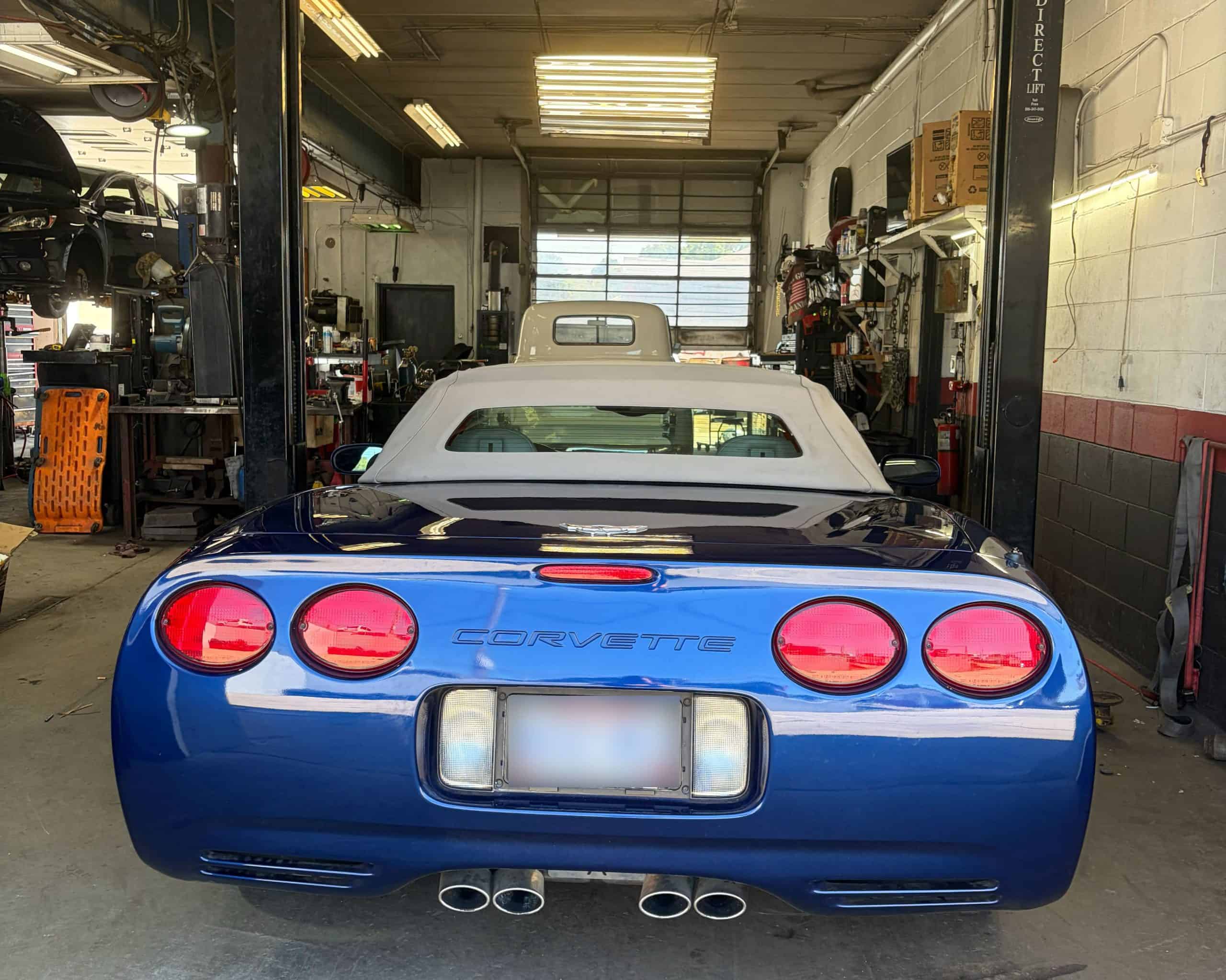 Blue Corvette in auto repair shop with tools and equipment.