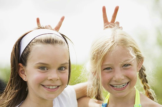2 young girls smiling giving rabbit ears