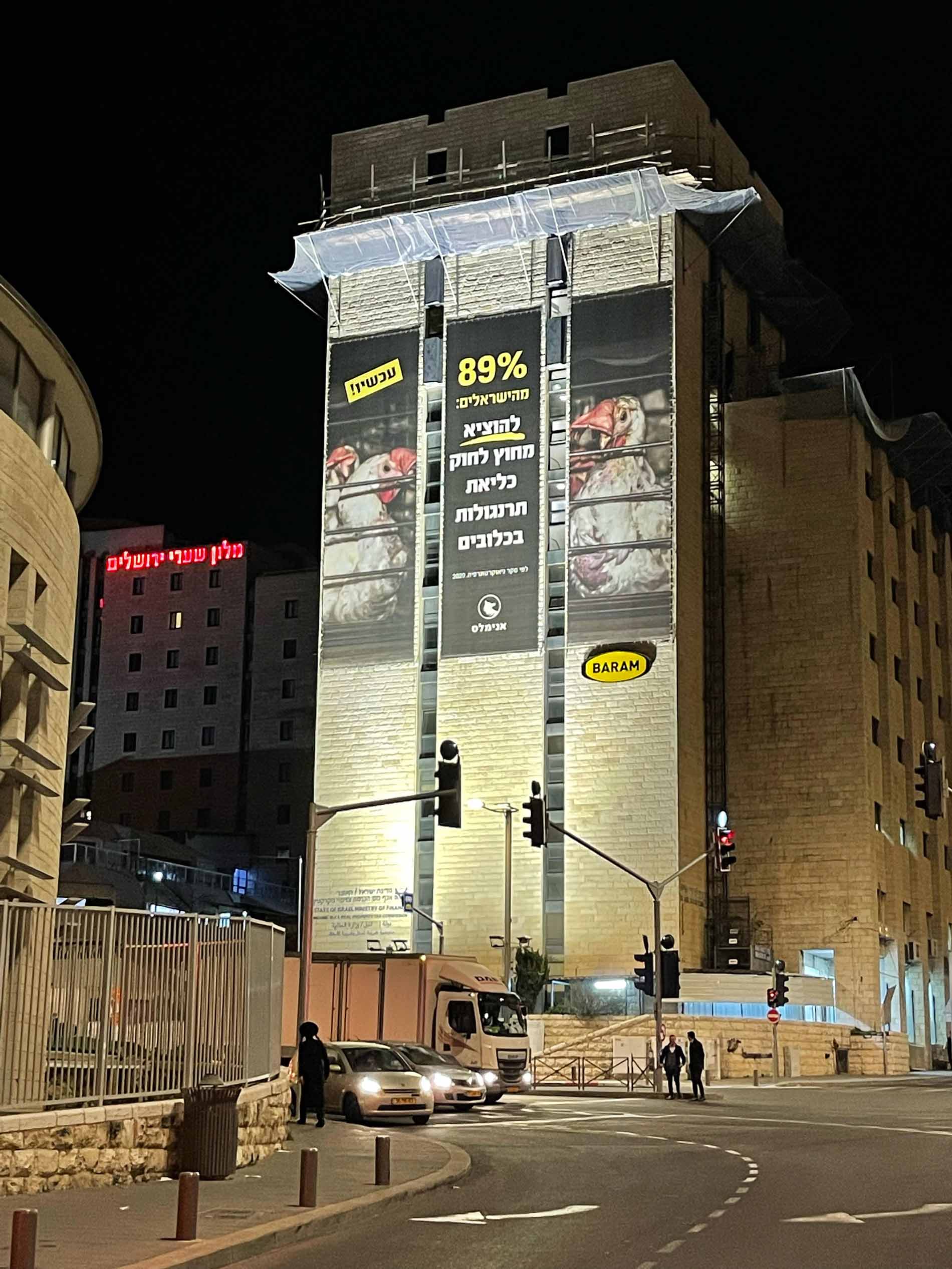 שלט חוצות נגד כליאת תרנגולות בכניסה לירושלים מצולם בלילה