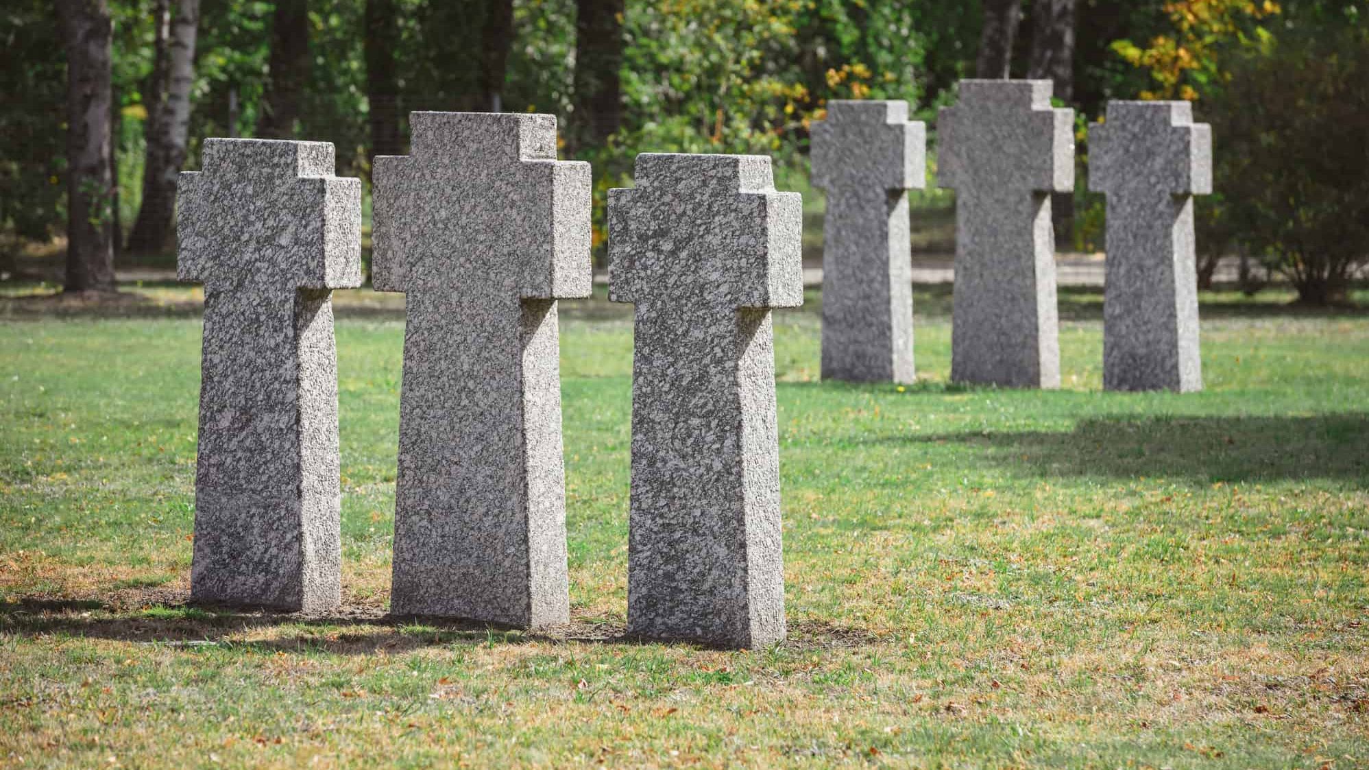 Selective focus of identical gravestones placed in rows at graveyard. Cemetary.