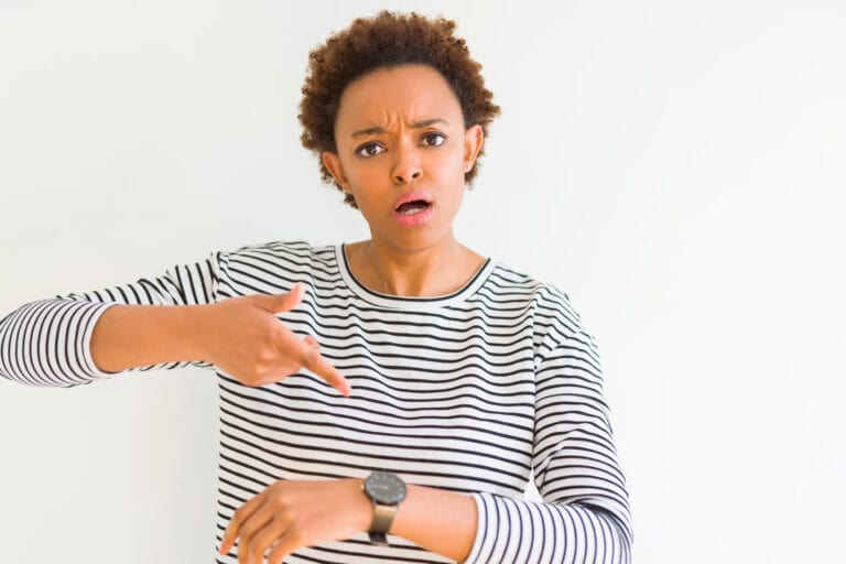 Young beautiful african american woman wearing stripes sweater over white background In hurry pointing to watch time, impatience, upset and angry for deadline delay