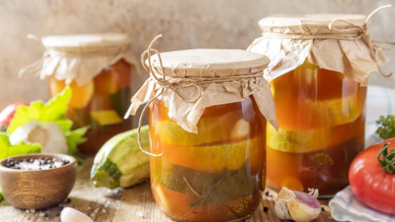 Healthy homemade fermented food. Marinated zucchini (courgette) in tomato sauce on a rustic table. Home economics, autumn harvest preservation.