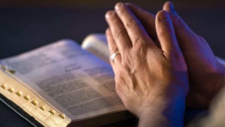 Hands on the Holy Bible. Prayer. Open Bible close-up. Religion concept.