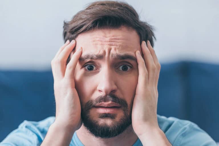 Selective focus of frightened man with hands on head