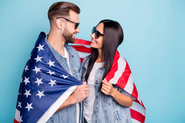 Profile side photo of cheerful married people having eyewear eyeglasses cover their denim jeans jackets with us flag isolated over blue background