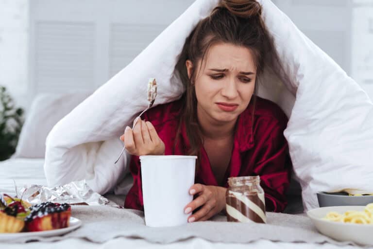 Stressed woman eating big ice cream and crying
