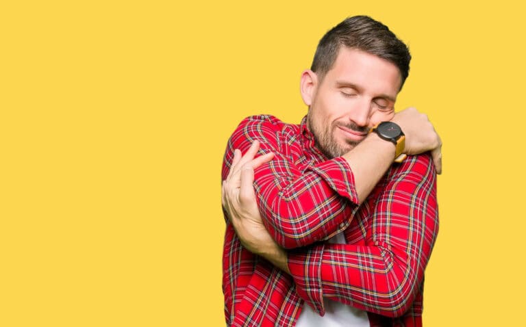Handsome man wearing casual shirt Hugging oneself happy and positive, smiling confident. Self love and self care