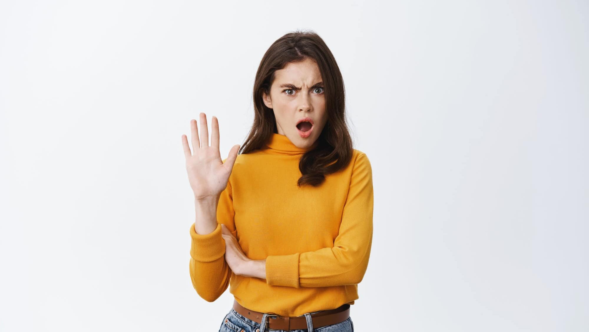 Stop right now. Offended and shocked woman showing block gesture, telling no, frowning and looking insulted with disgusting offer, refusing, standing against white background.