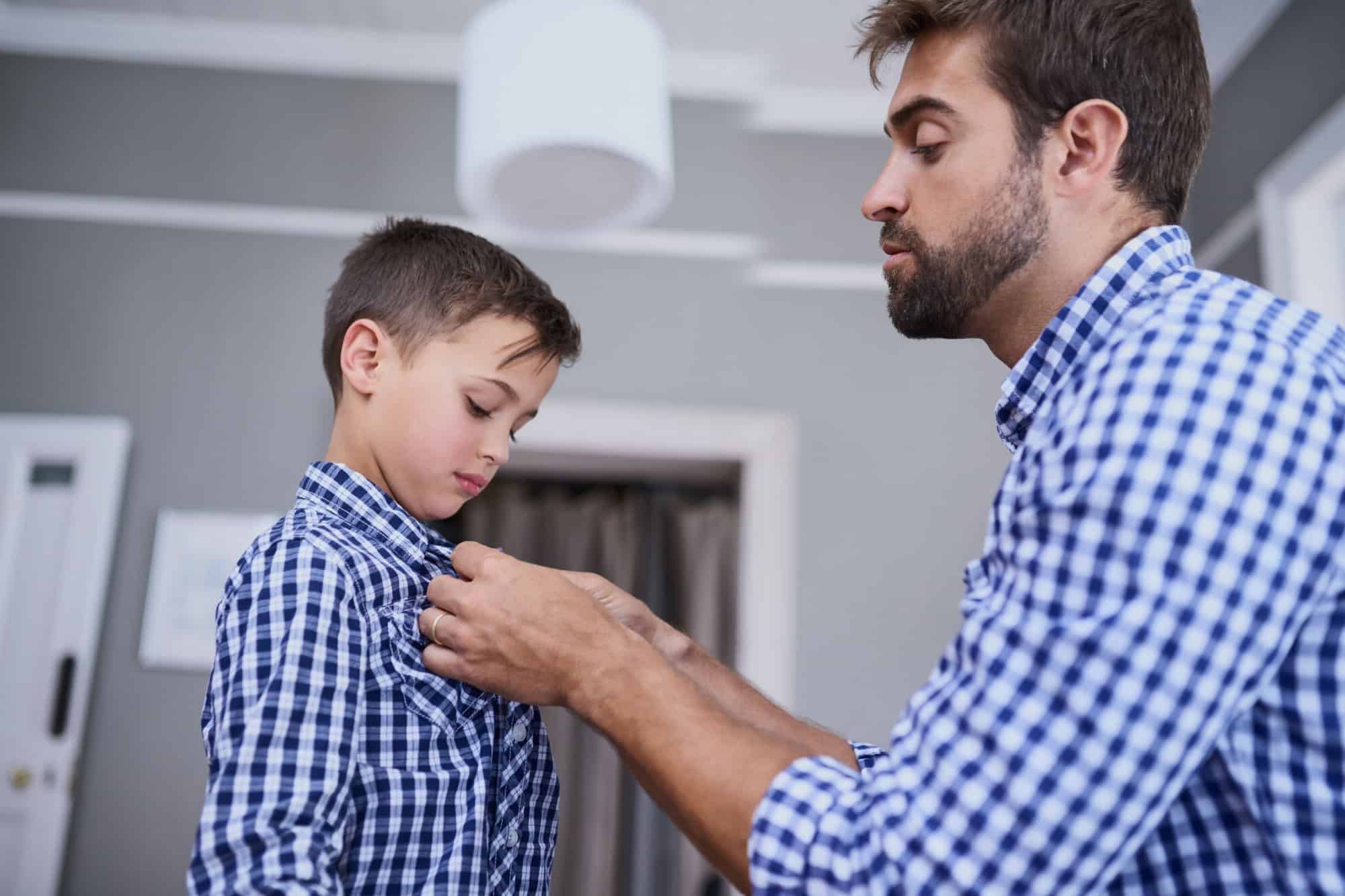 Let me help you with that button. Cropped shot of a handsome young man and his son getting dressed in the morning.