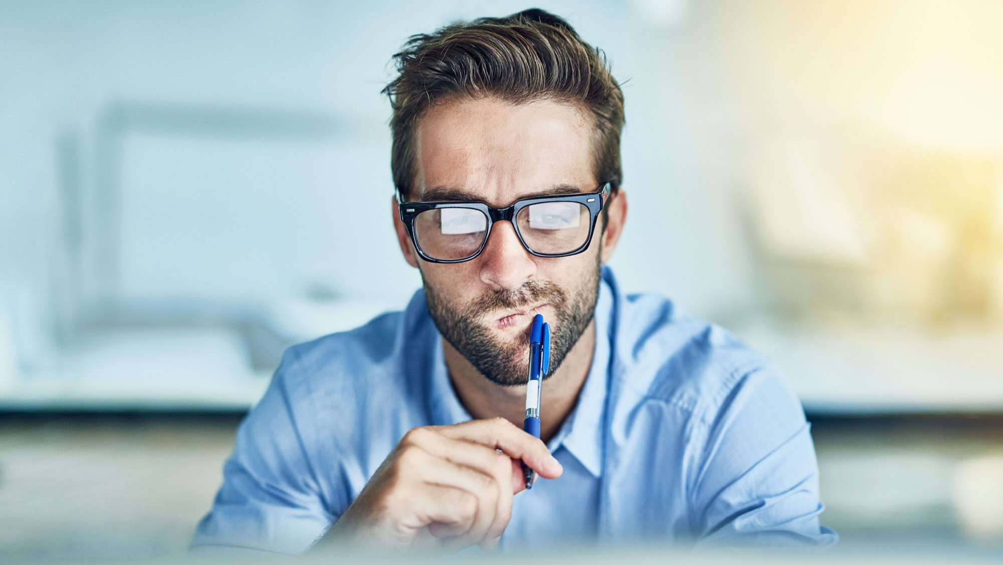 Desk, employee and man in office, thinking and brainstorming of idea, startup and copywriting in business. Workplace, staff and person with glasses, question and working in agency and innovation