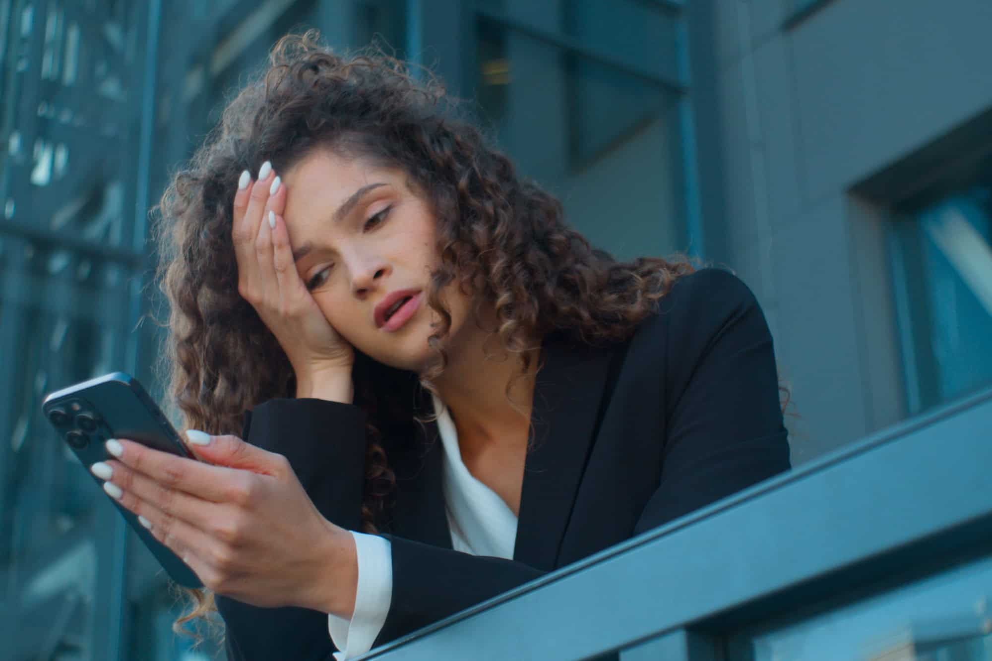 Caucasian young girl business woman employee worker tired exhausted upset stressed sad businesswoman on office balcony outside problem failure mobile phone bad news smartphone message in city outdoors