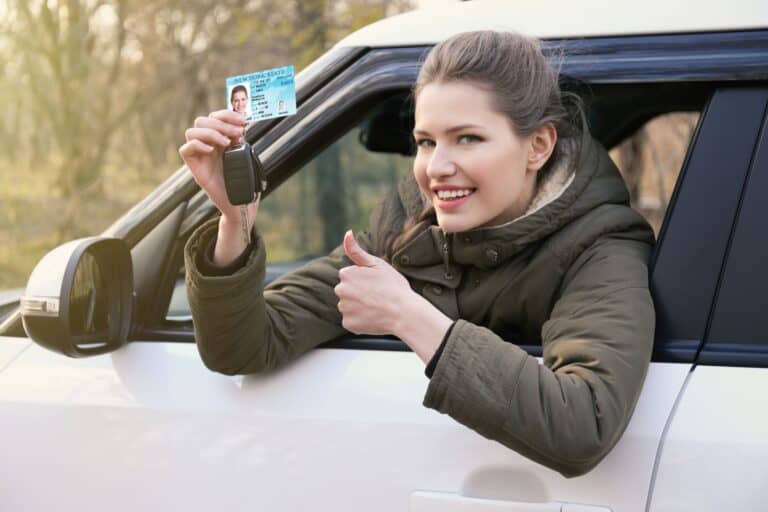 Woman with driving license and key in car