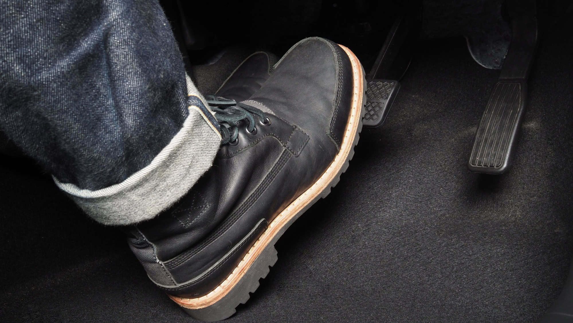 Comfortable black leather wedding shoes on a car pedal for men during driving.