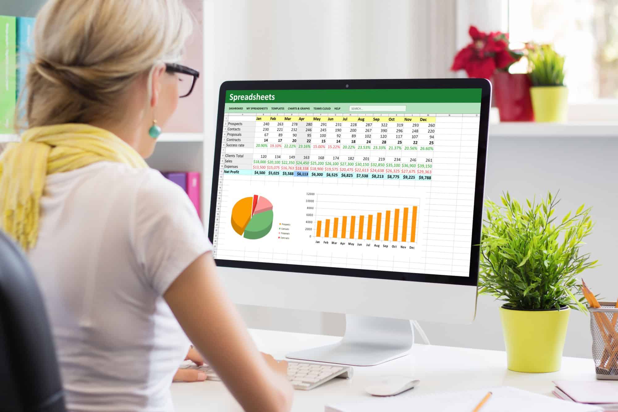Woman working with data and graphs in spreadsheet document on desktop computer