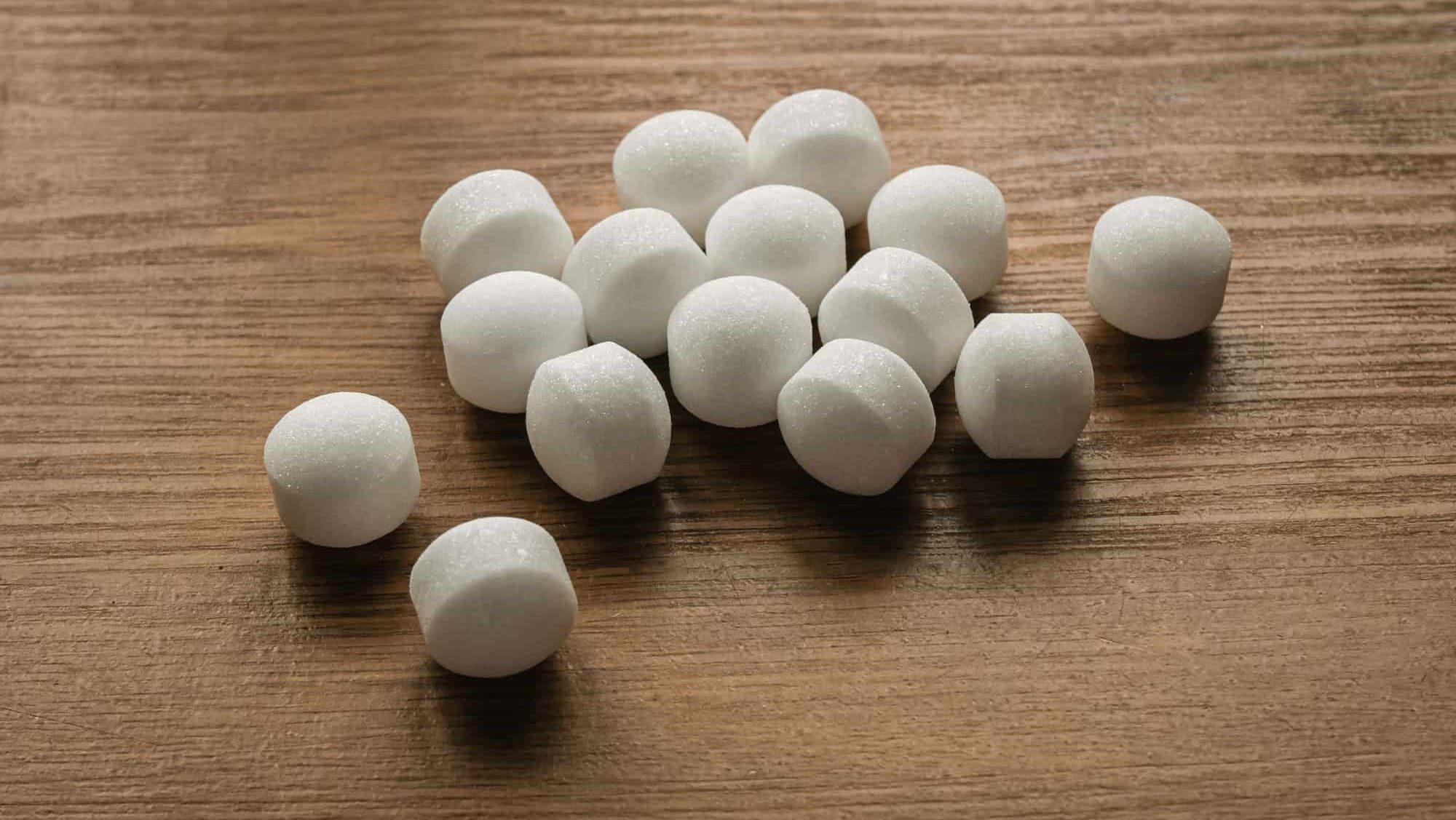 Naphthalene mothballs on wooden background.