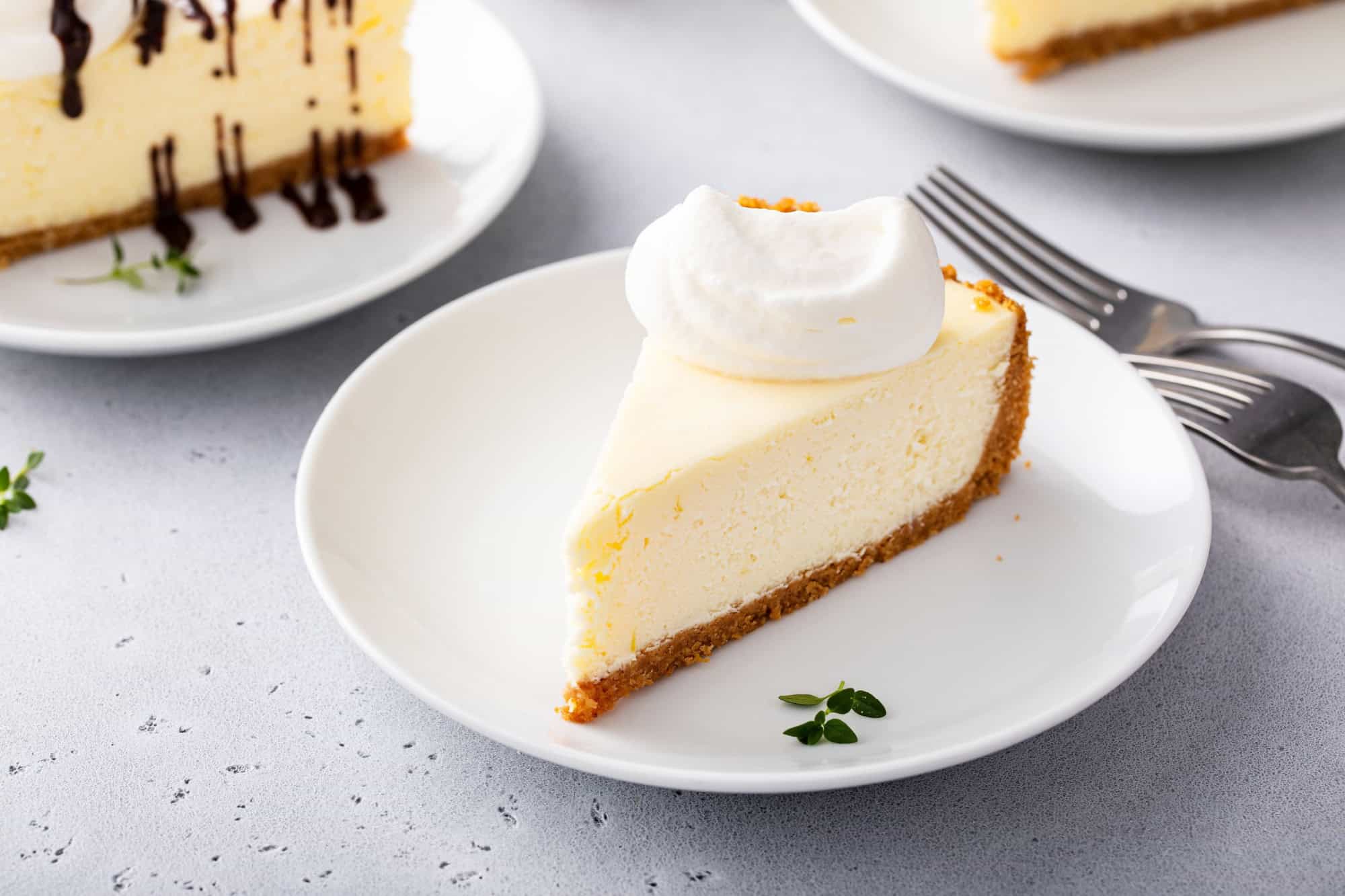 Slice of a traditional New York cheesecake with dollop whipped cream
