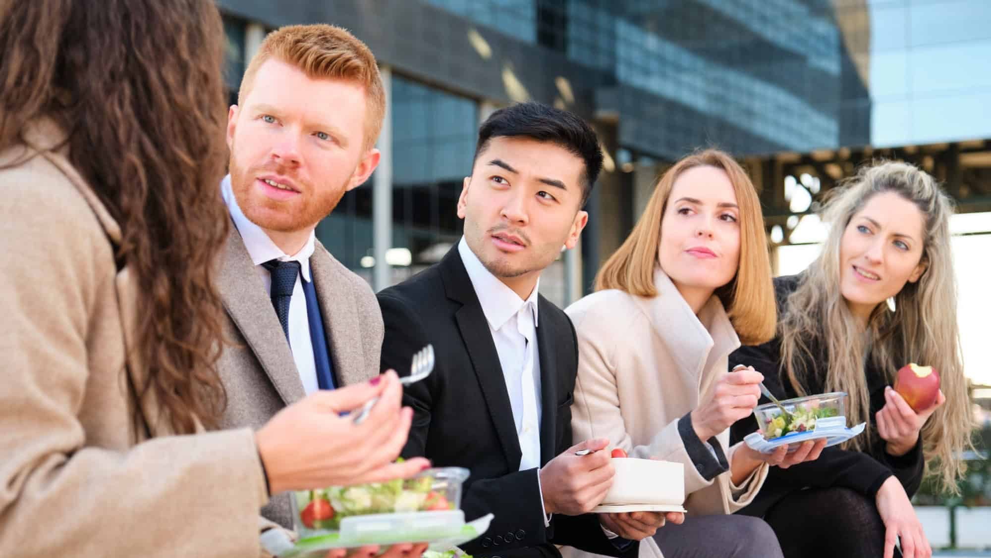 Businesswoman talking to her international colleagues during the lunch break outside the office building.
