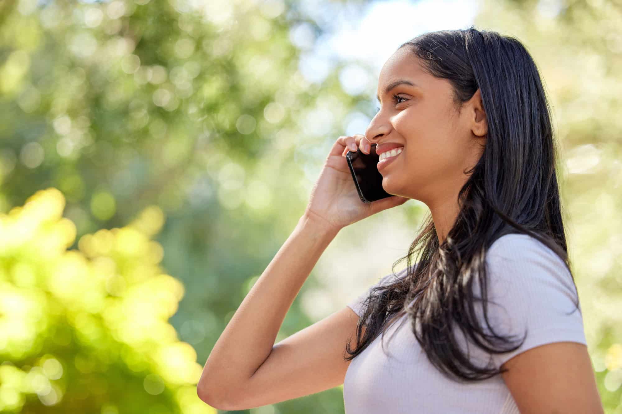 Phone call, talking and woman with smartphone in park for conversation, networking or gossip. Bokeh, smile and profile of female person with mobile for speaking, exciting news or discussion in nature