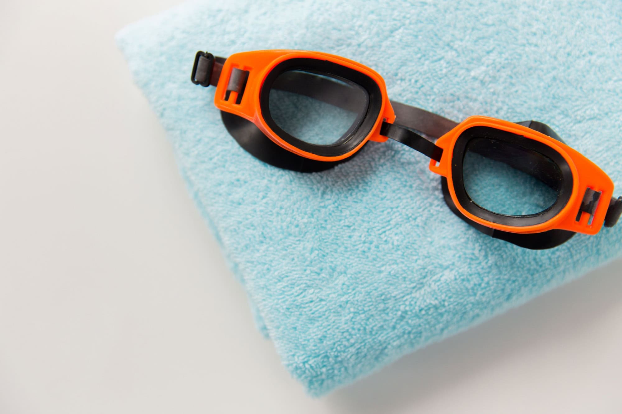 Sport, fitness, water sports and objects concept - close up of swimming goggles and towel