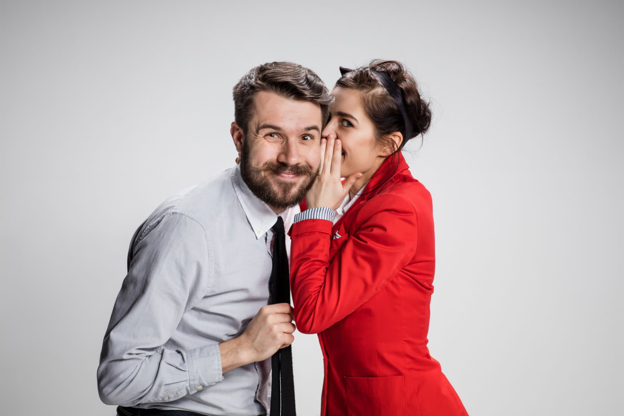 Young man telling gossips to his woman colleague at the office