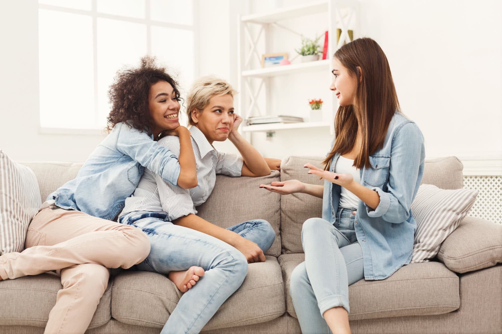 Happy female friends chatting at home. Three young women having friendly talk, gossiping and smiling, slumber party, copy space