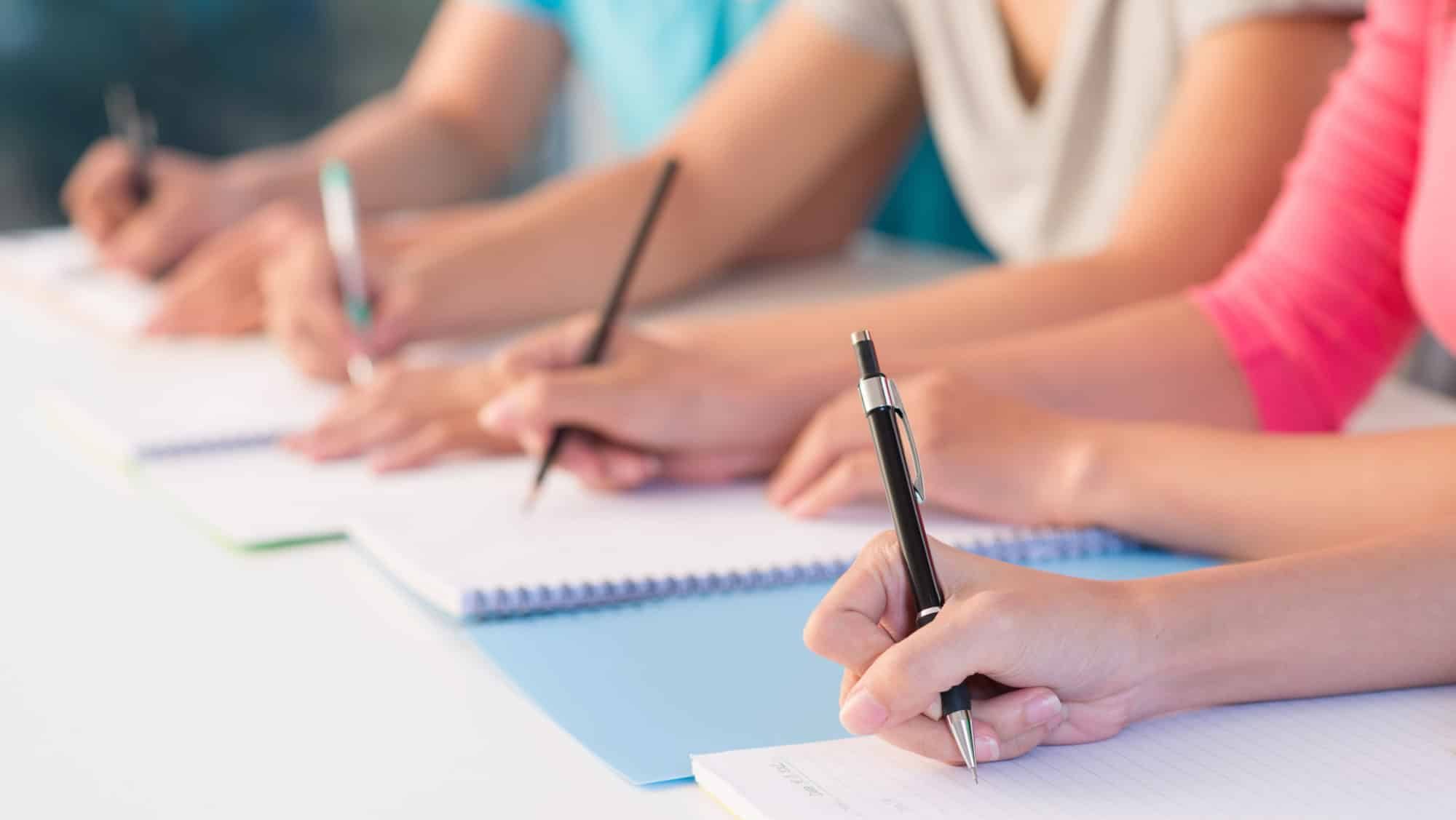 Close-up of writing hands of students at school