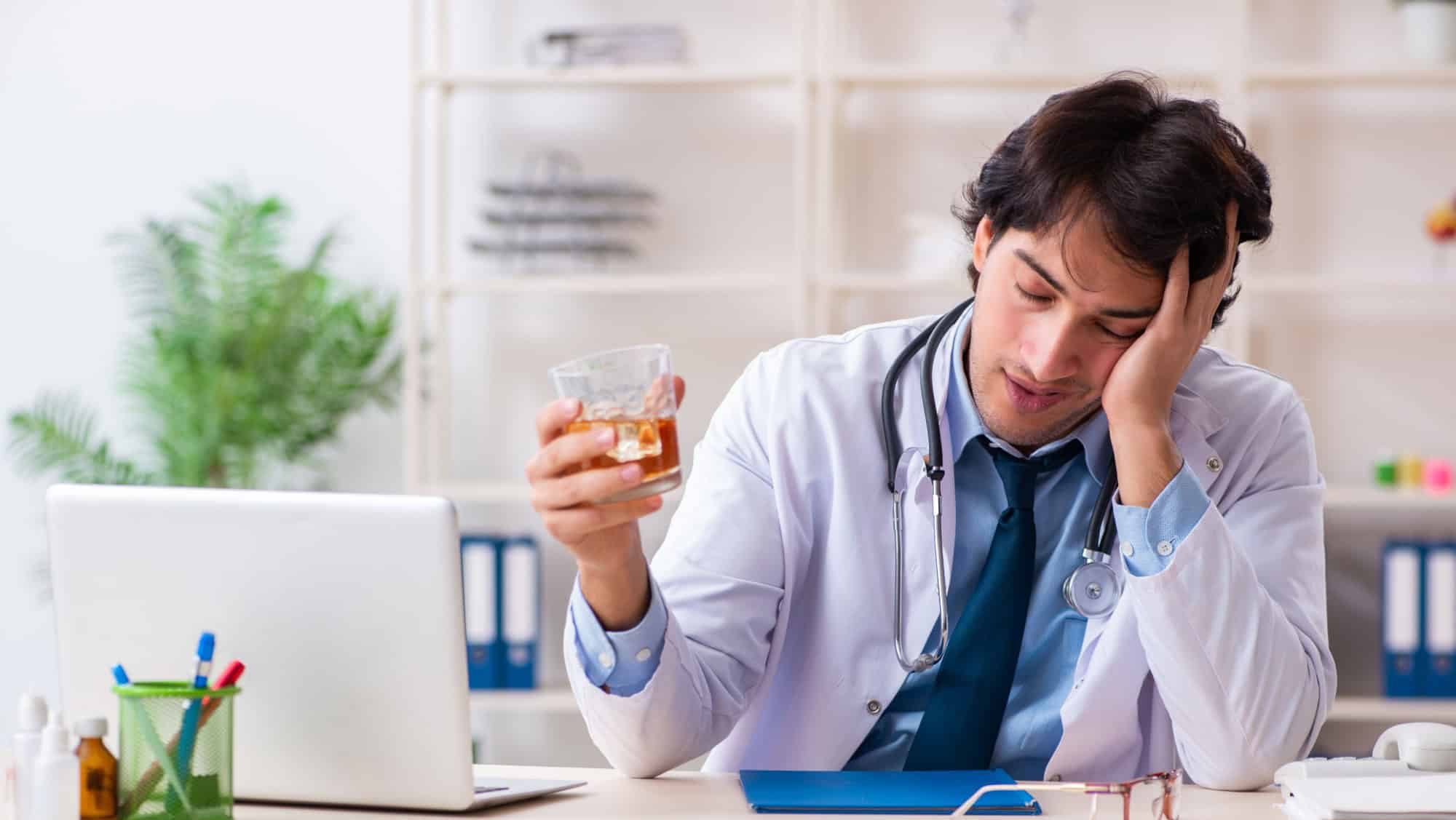 Young male doctor drinking in the office