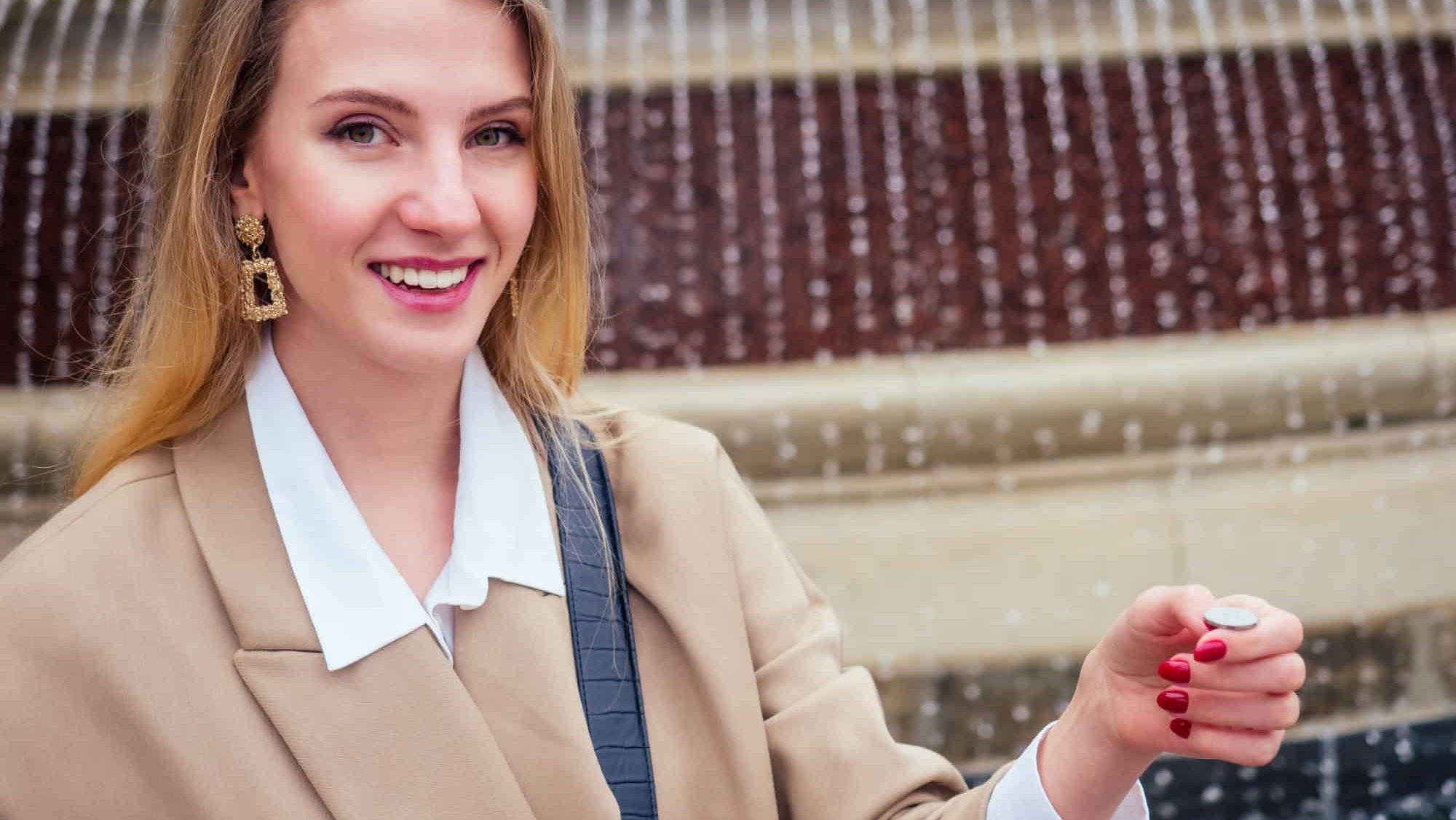 Young blonde woman makes a wish at a fountain