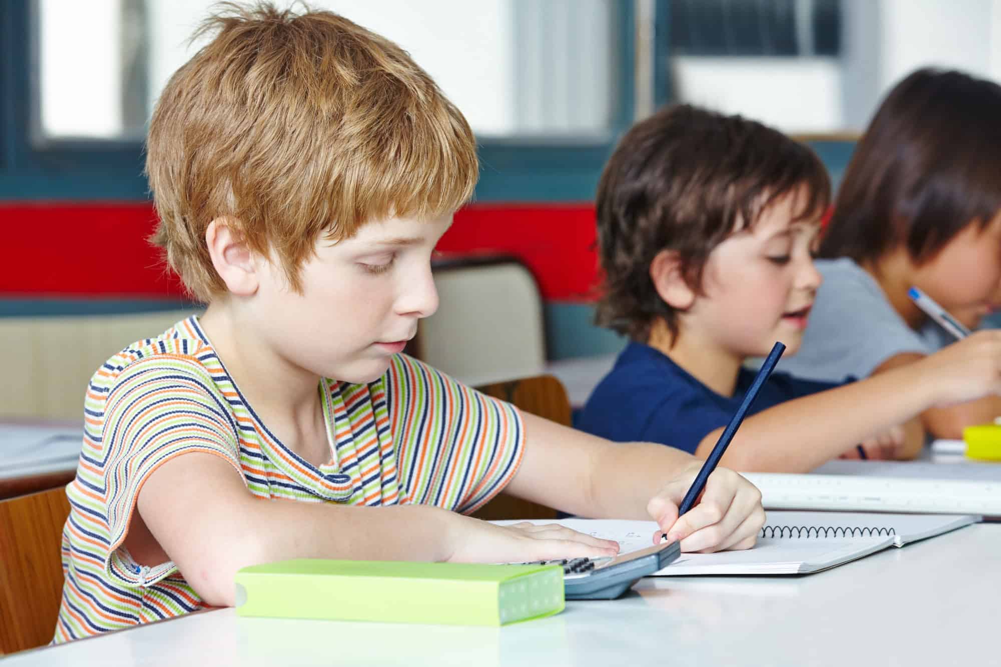 Lefthanded boy in elementary school writing with a pencil
