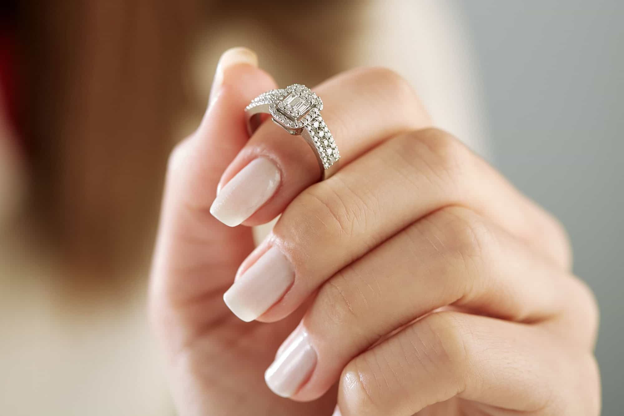Burn an elegant diamond ring on the female finger. Love and wedding concept. Soft and selective focus.