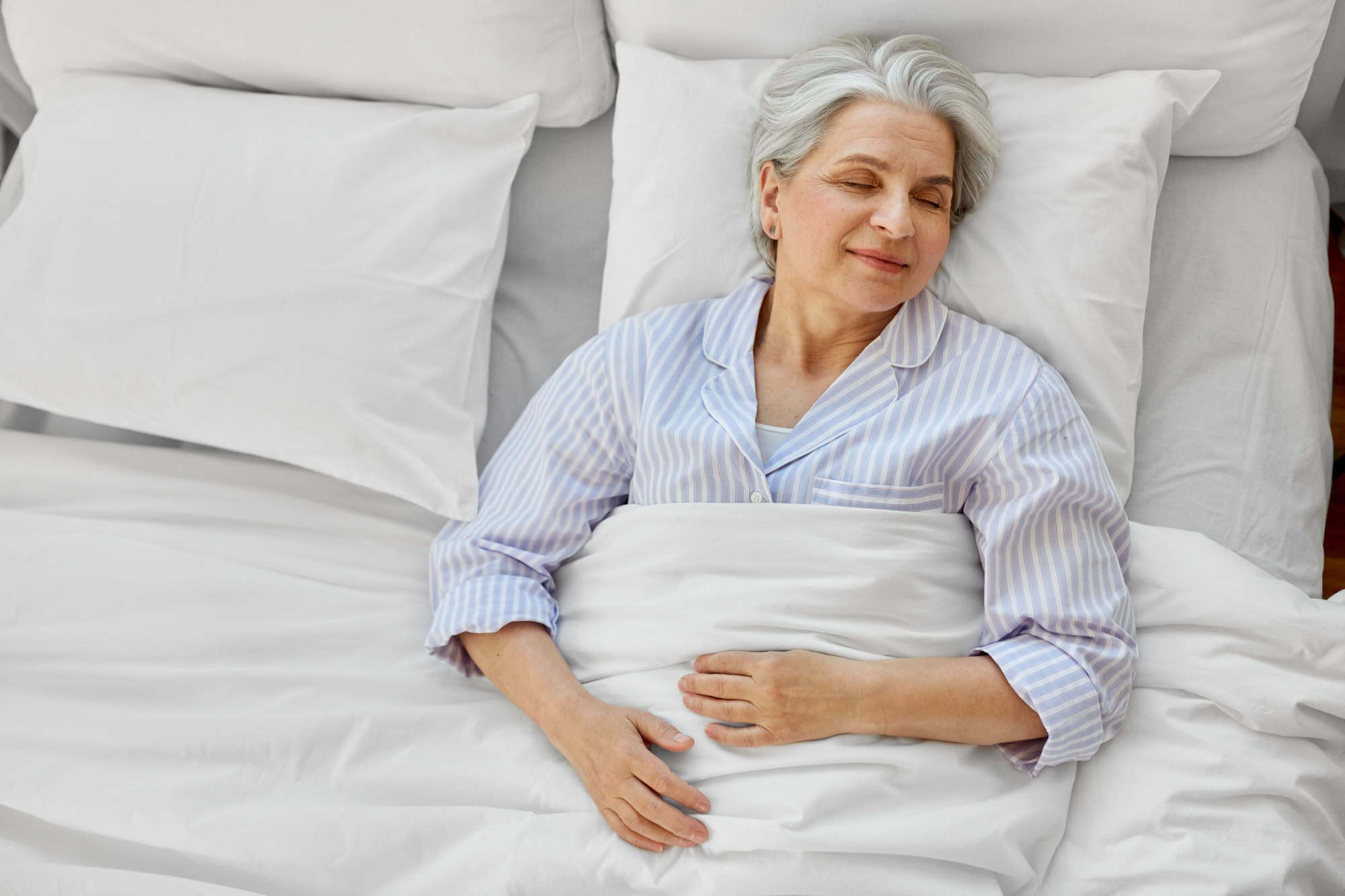 Old age and people concept - happy senior woman sleeping in bed at home bedroom