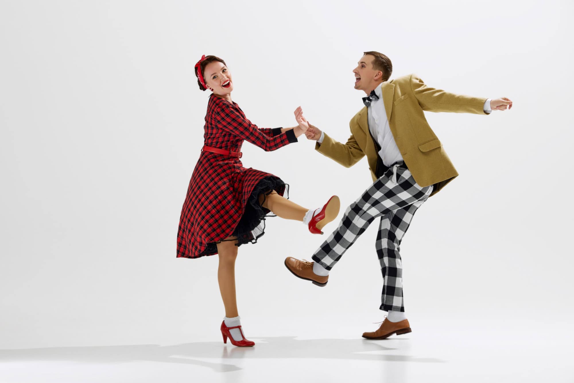 Retro dance scene with young stylish man and beautiful woman in red dress dancing joyously isolated over white studio background. Concept of art, retro and vintage, hobby, entertainment, 20s