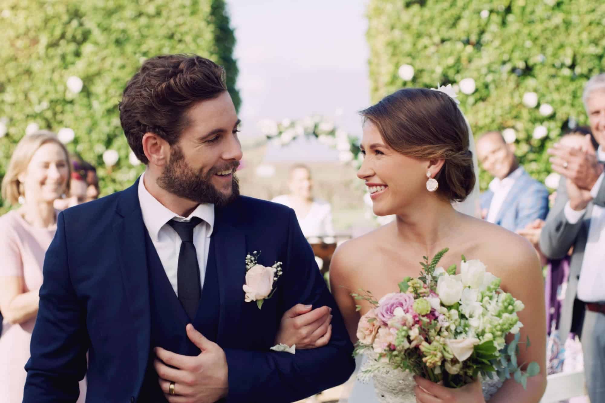 Wedding, couple and love at celebration with smile, friends and family at venue. Bride, groom and happiness at marriage for commitment, bouquet and audience with applause and excited for union