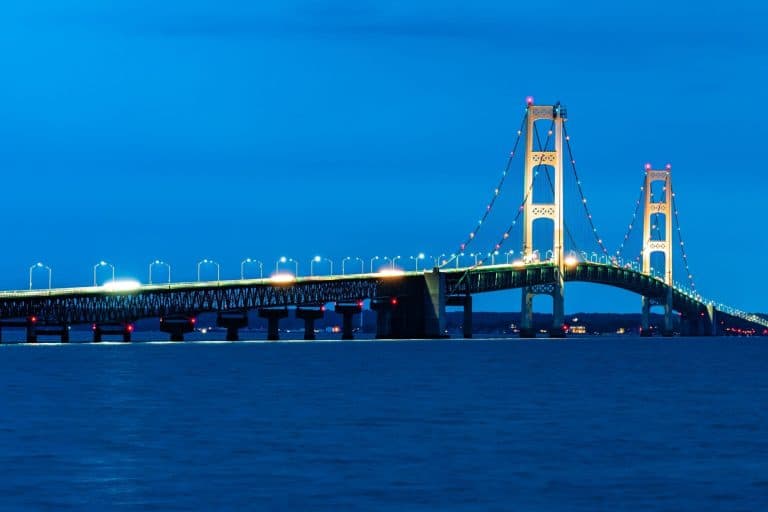 The Mackinac Bridge illuminated against a blue sky, spanning across the Straits of Mackinac in Michigan