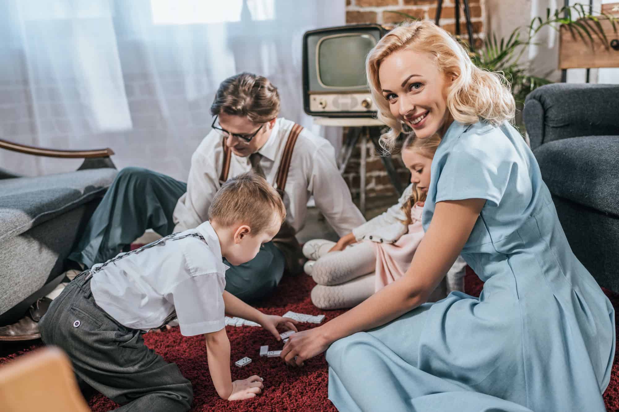 Vintage happy family playing board game and woman smiling at camera, retro style