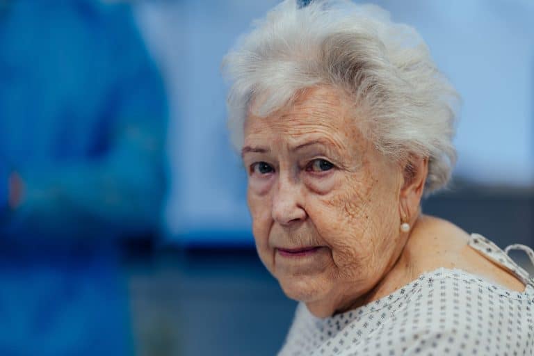 Portrait of scared senior patient on examination table in the hospital. Concept of fear and anxiety about health problems in elderly people.