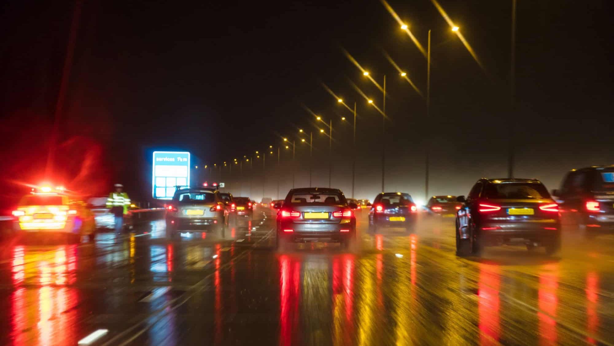 Motion blurred photograph of traffic at in night in the rain on a British motorway with police officer and car