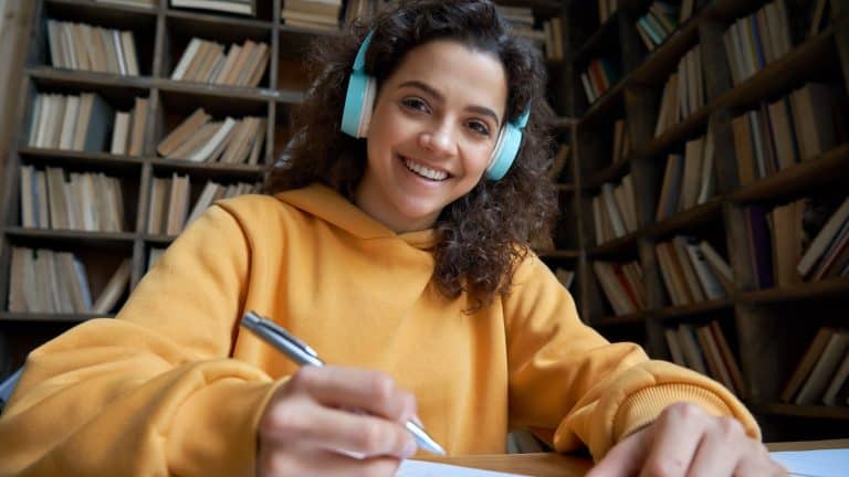 Smiling hispanic teen girl school student wear headphones looking at webcam distance learning. Zoom video call remote class, online lessons and courses concept. Headshot portrait. Webcamera view.