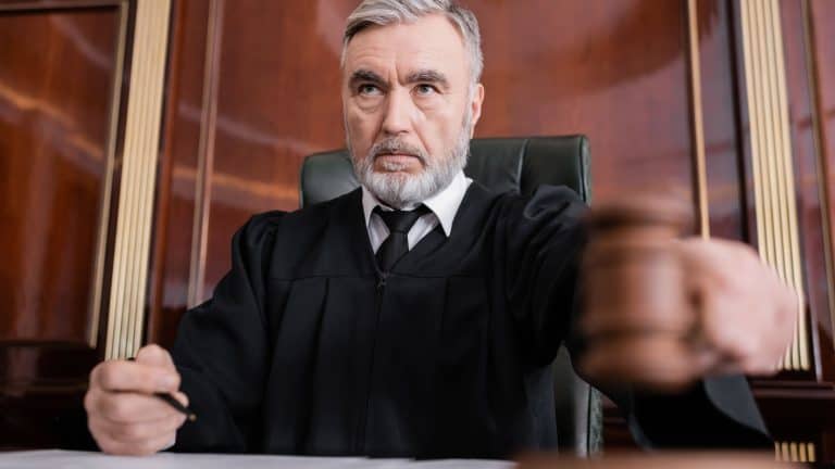 Senior judge in mantle holding blurred gavel while sentencing in court