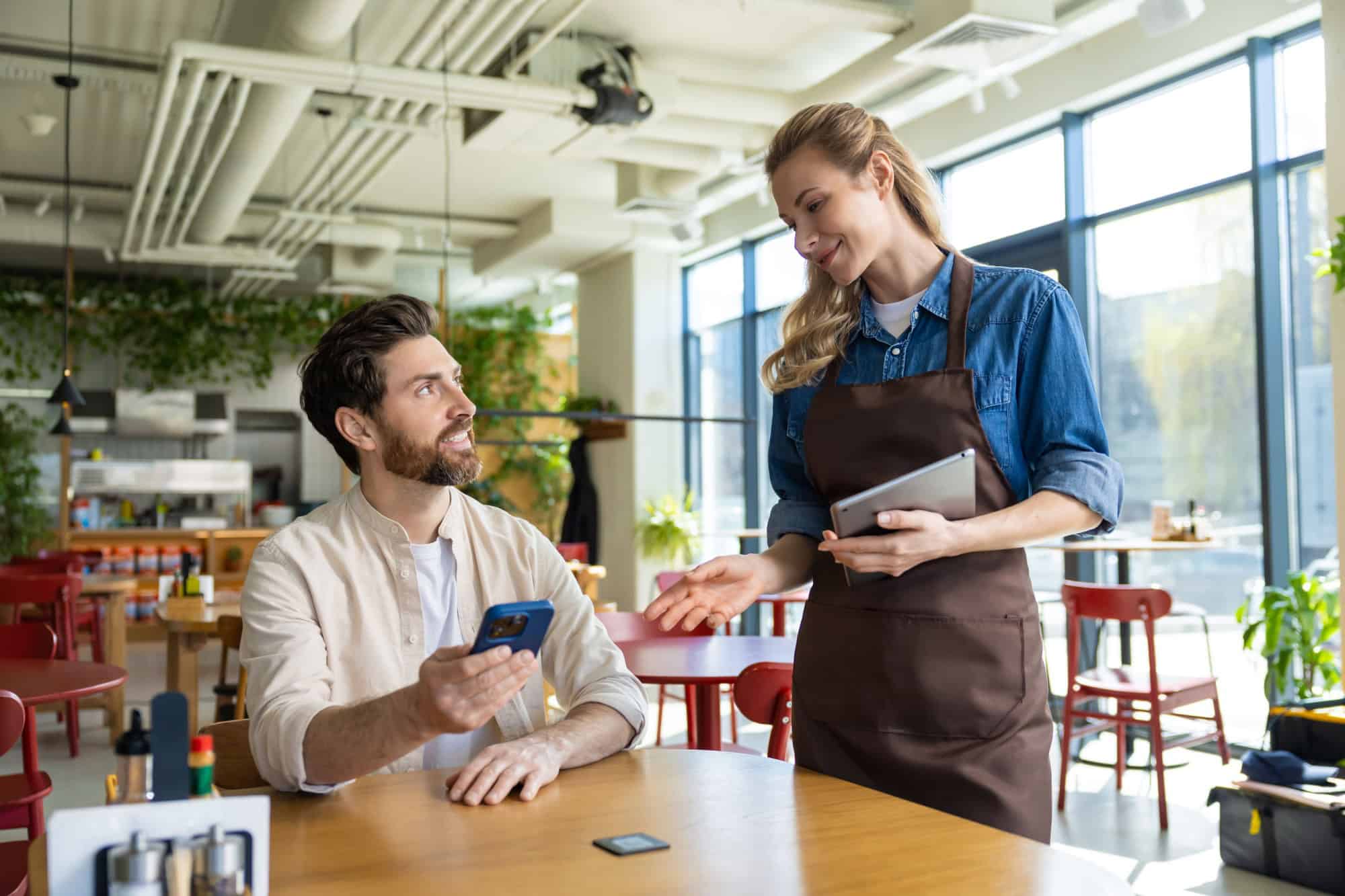 Man consulting phone while ordering at restaurant