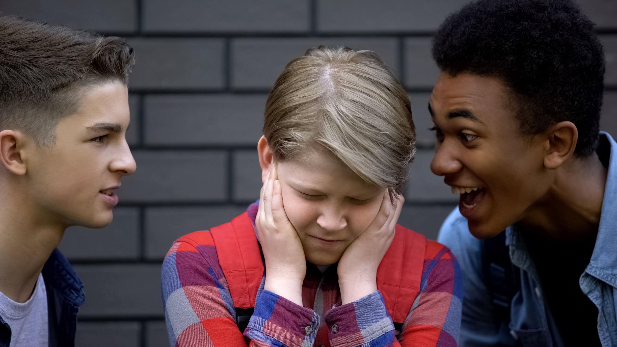 Angry high school students teasing boy calling names, face-to-face bullying
